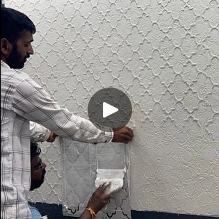 two men are working on a wall with white paint and paper towels in front of them