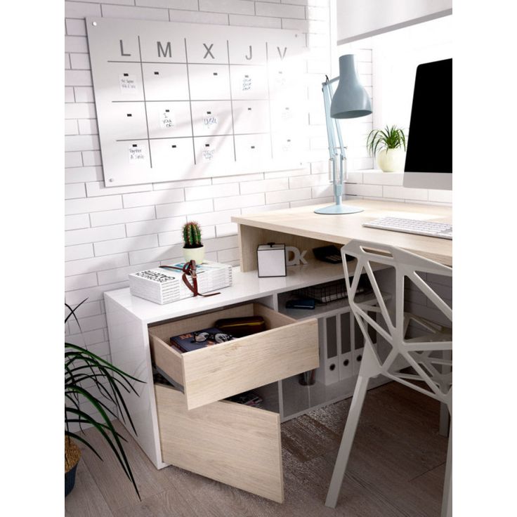 a desk with a computer on it in front of a white brick wall and potted plants