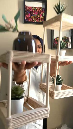 a woman is holding up some shelves with succulents on them in front of her face