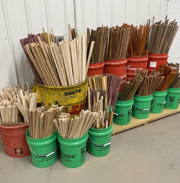 several buckets filled with sticks sitting on top of a shelf next to each other