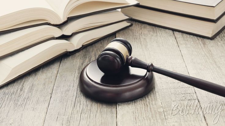 a judge's gavel sitting on top of an open book next to a stack of books