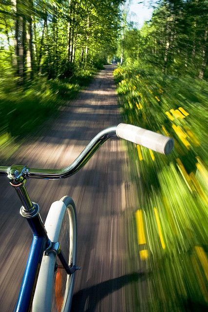 a blurry photo of a bicycle riding down a road with a sign in the background