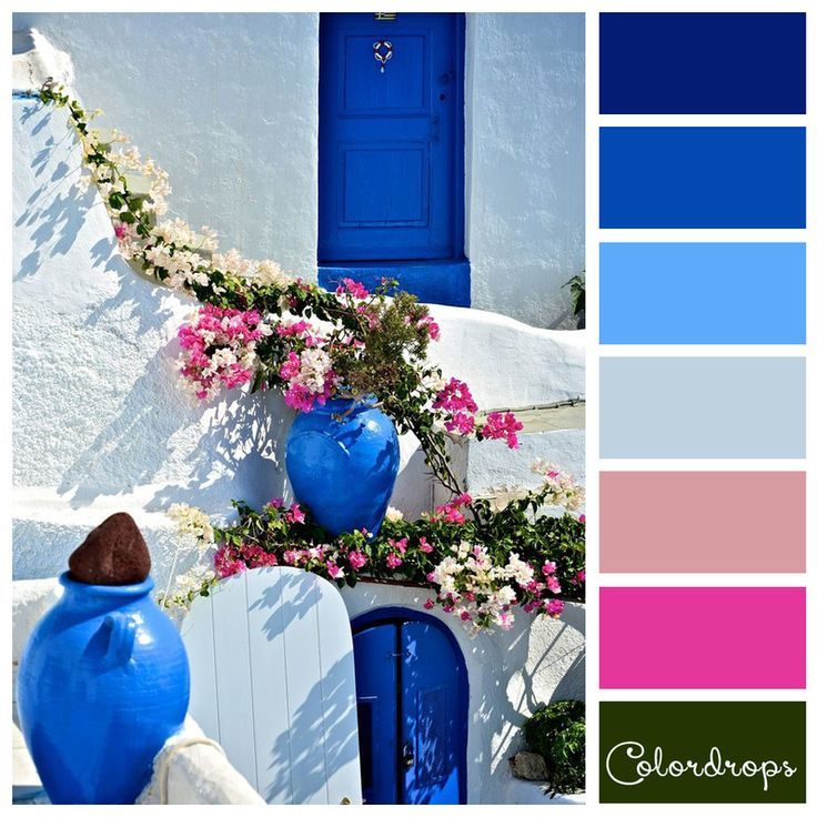 blue vases with pink and white flowers on the side of a building in greece