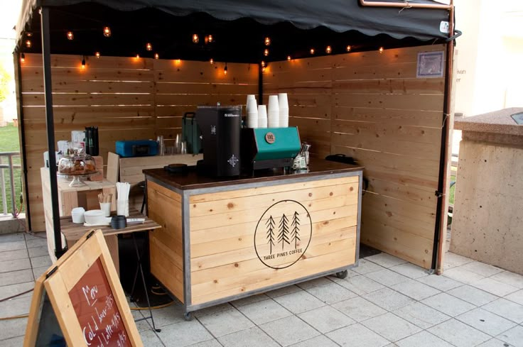 an outdoor coffee shop with lights strung over the top and wood paneling on the outside