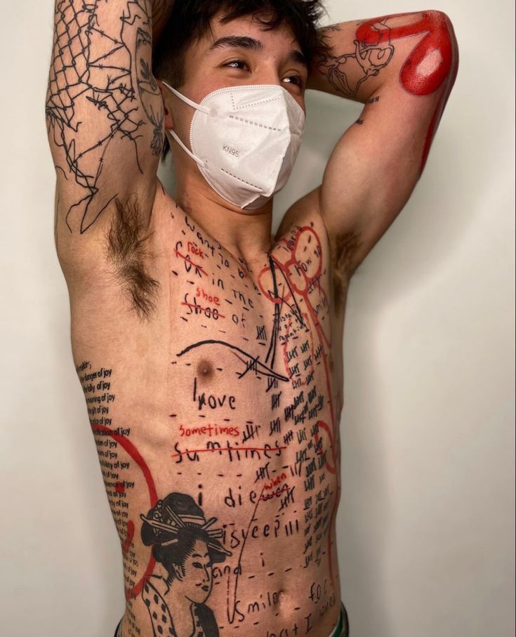 a man with tattoos and a face mask covering his face is posing for the camera