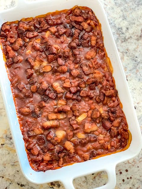 a white casserole dish filled with beans and sauce on top of a marble counter