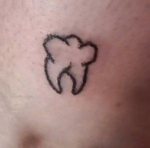 a small tooth tattoo on the stomach