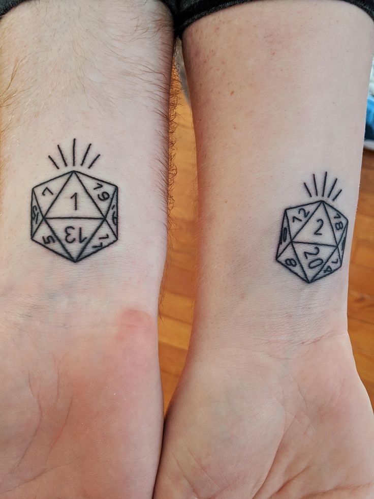 two people with matching tattoos on their wrists, one has a dice and the other has a sunburst