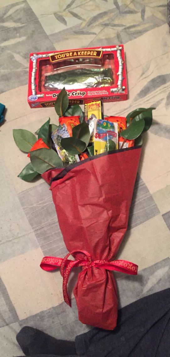 a red bag filled with candy sitting on top of a bed next to a plant