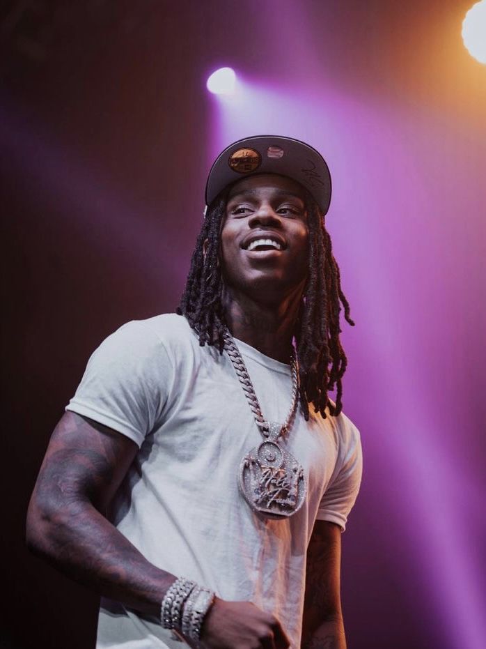 a man with dreadlocks standing on stage in front of purple and yellow lights