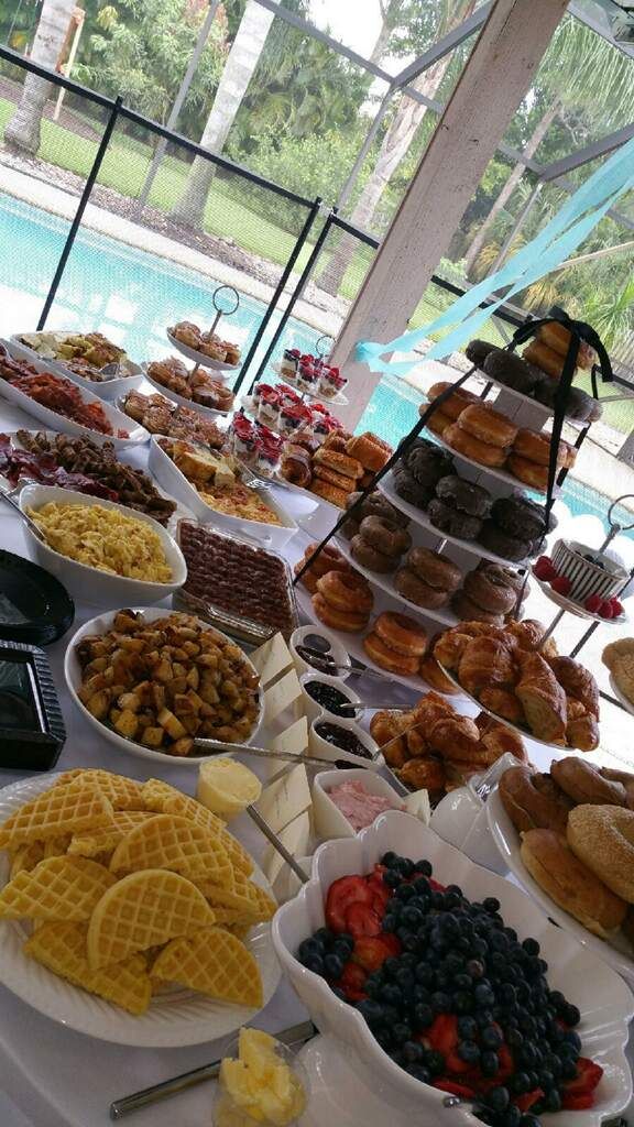 a table filled with lots of different types of foods and desserts on plates next to a swimming pool