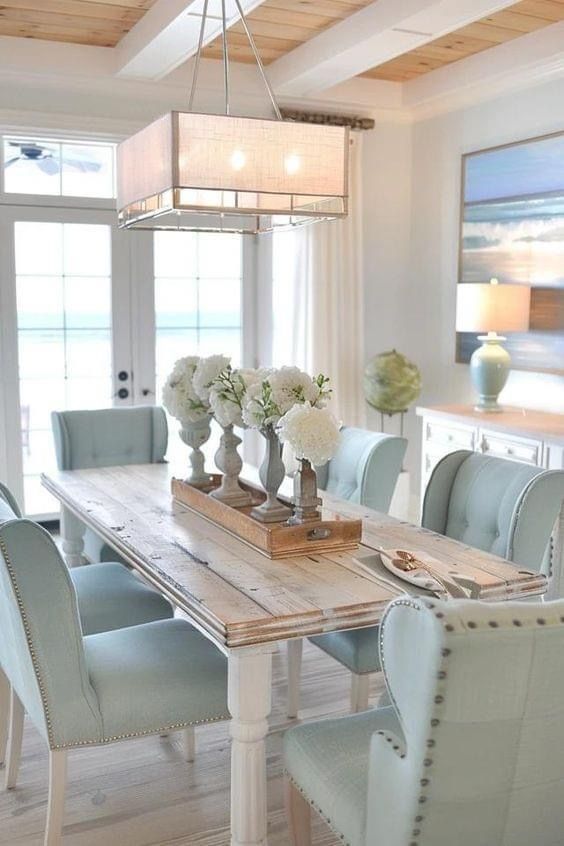 a dining room table with blue chairs and white vases on top of the table