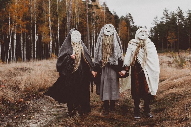 three people with masks on their faces are standing in the woods