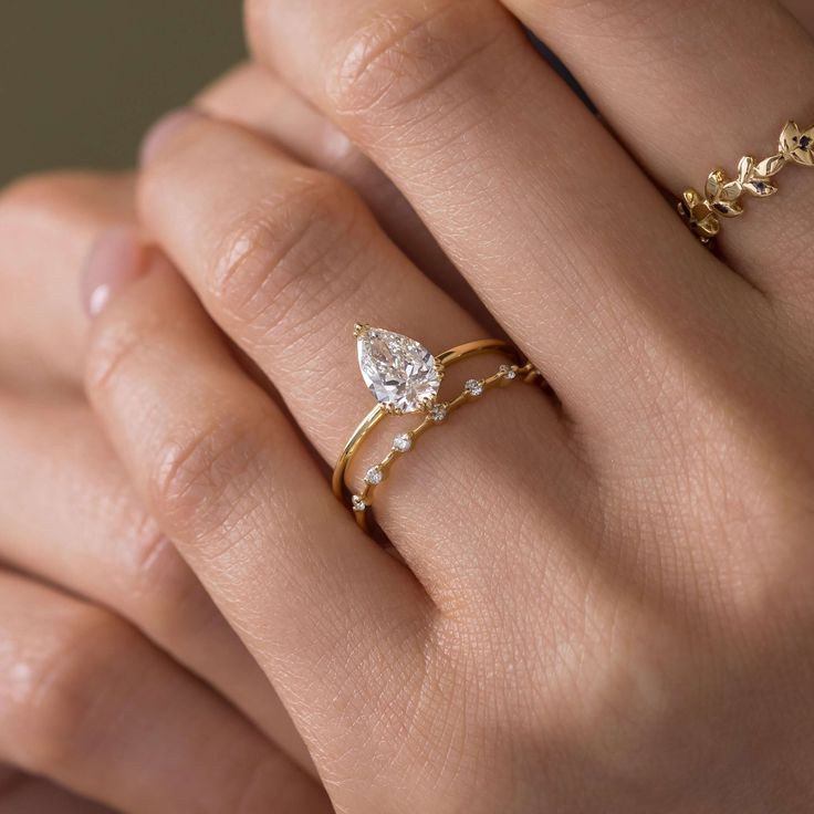 a woman's hand with two gold rings and one diamond ring on her finger