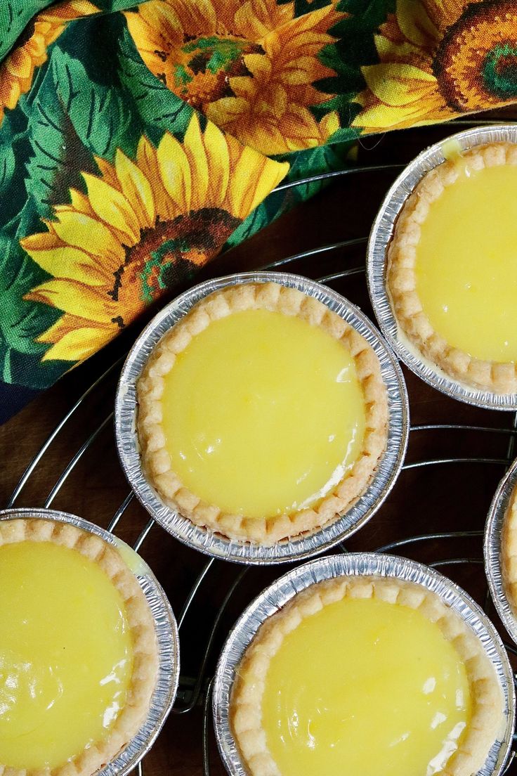 four pies sitting on top of a metal rack next to a flowery cloth