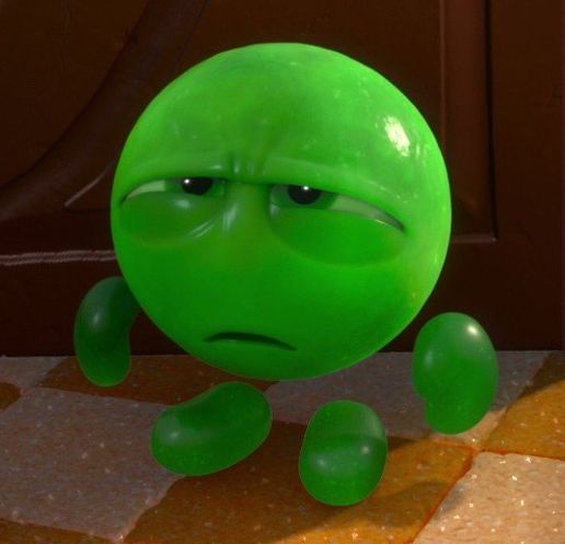 a green ball with an angry look on it's face sitting on the ground