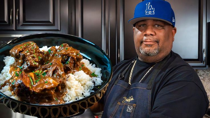 a man holding a plate of food with meat and rice