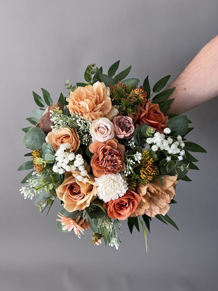 a bouquet of flowers is being held up by someone's hand on a gray background