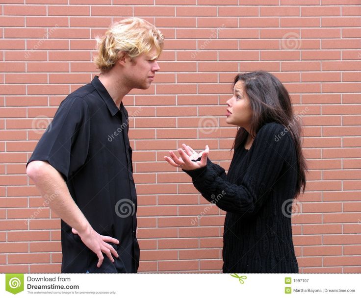 a young man and woman standing next to each other in front of a brick wall