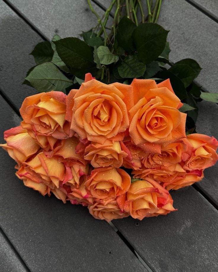 a bouquet of orange roses sitting on top of a wooden table