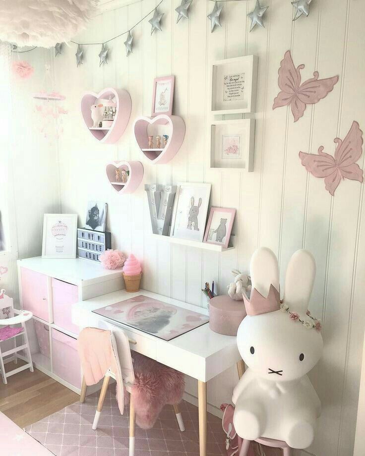 a white desk topped with a stuffed animal next to a wall covered in pink hearts