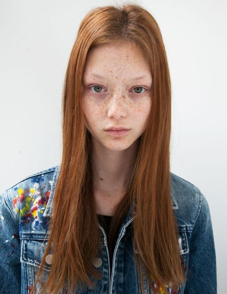 a woman with freckles on her face and long red hair is looking at the camera