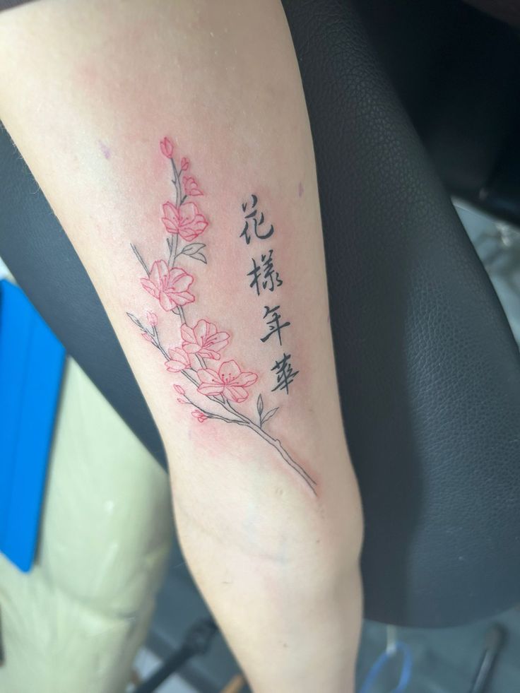 a woman's arm with chinese writing on it and flowers in the middle of her arm