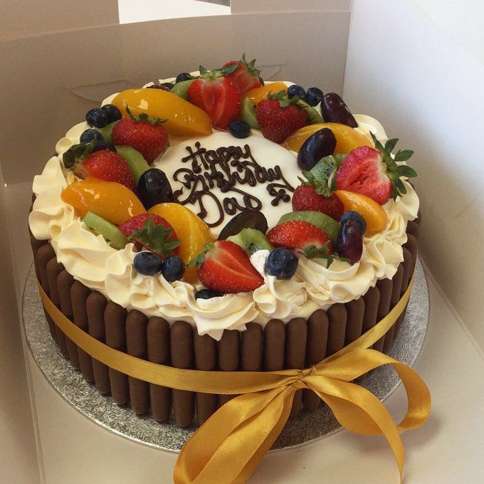 a birthday cake decorated with fresh fruit and chocolate icing in a box on top of a table