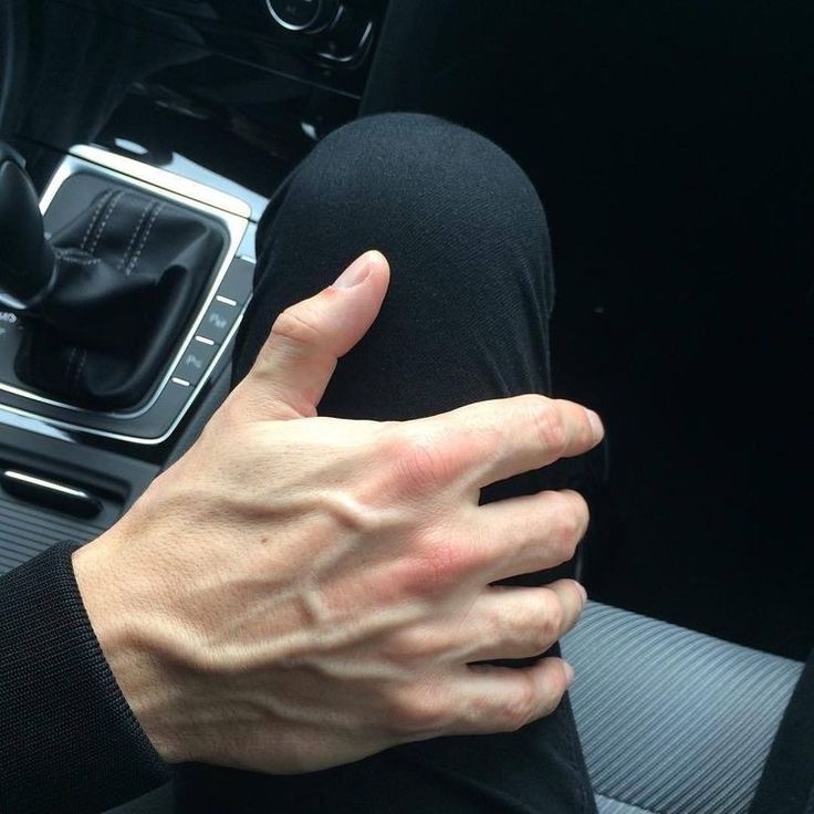 a person with their hand on the center console of a car, while wearing black gloves