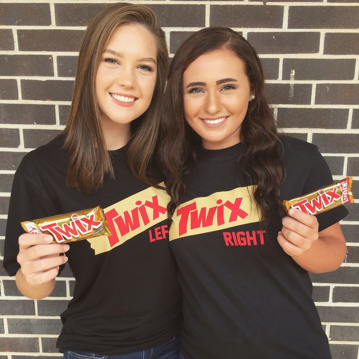 two young women holding up twinkies in front of a brick wall