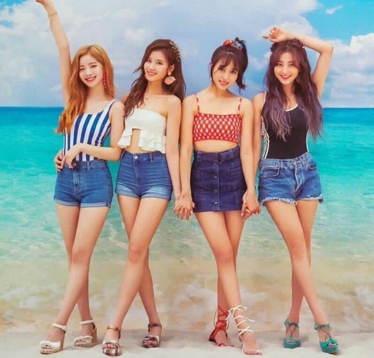 four girls standing on the beach with their arms in the air