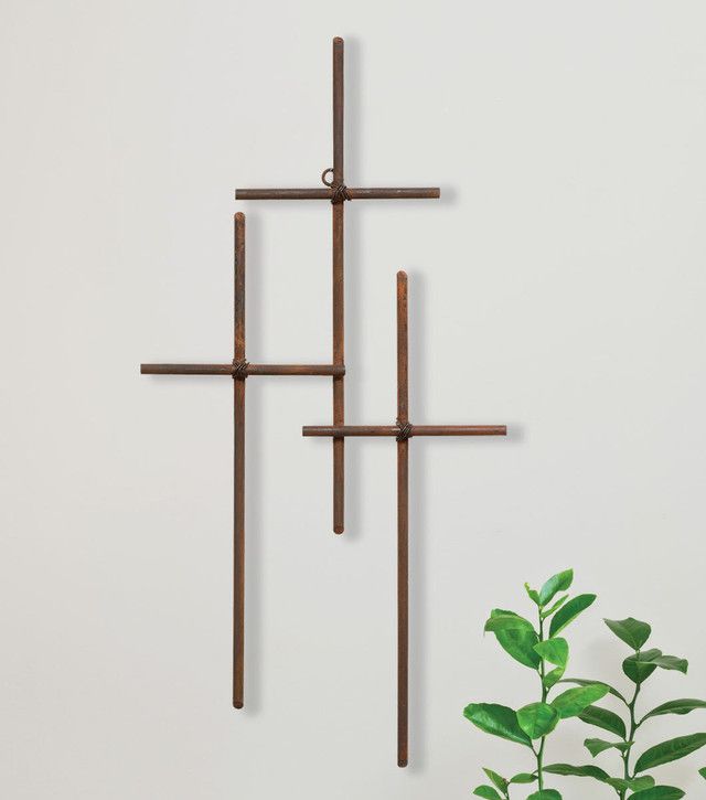 three crosses hanging on the wall next to a potted plant