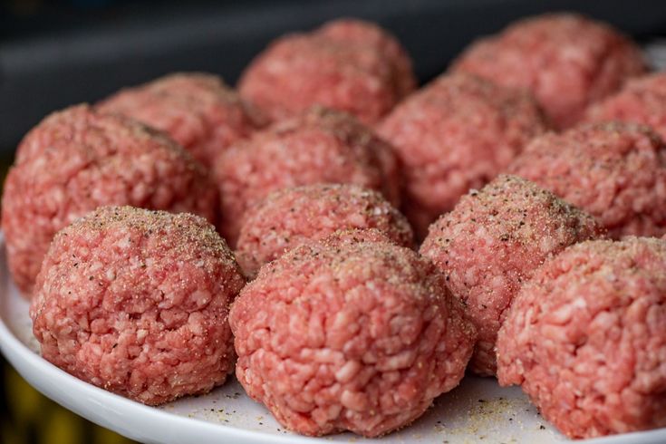 a white plate topped with meatballs covered in seasoning on top of a table