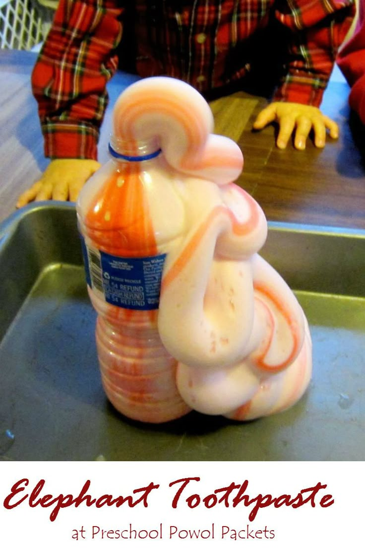 a plastic doll sitting on top of a metal tray next to a bottle of liquid