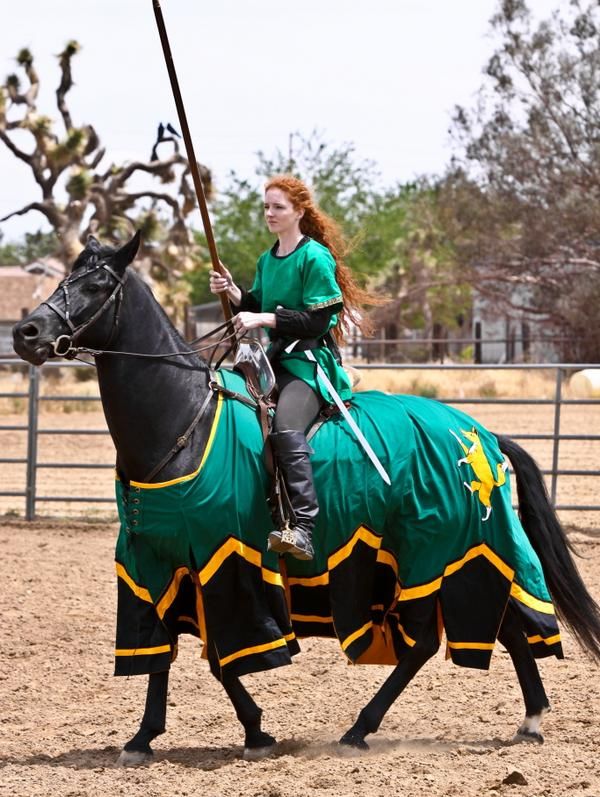 a woman riding on the back of a black horse in a corset and green outfit