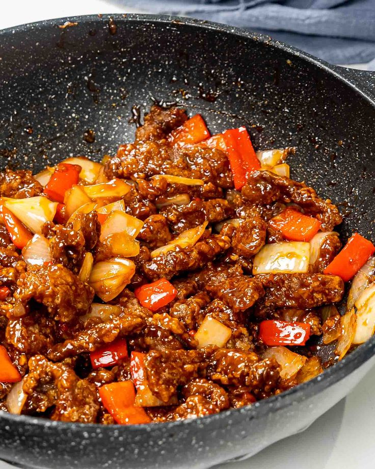 meat and vegetables cooking in a skillet on the stove top, ready to be cooked