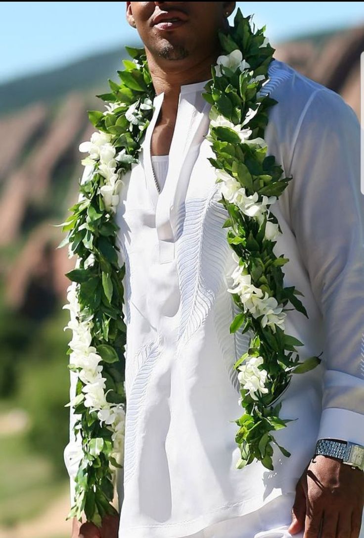 a man in white shirt and lei with flowers around his neck