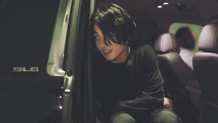 a young man sitting in the passenger seat of a car