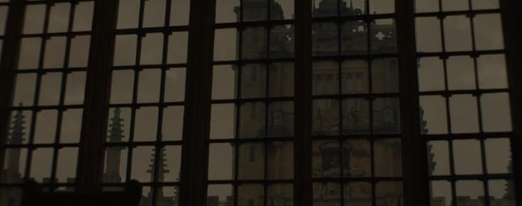 the clock tower is seen through many windows in an old building with iron bars on it's sides