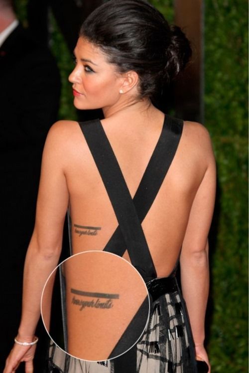 the back of a woman's dress with tattoos on her upper and lower back