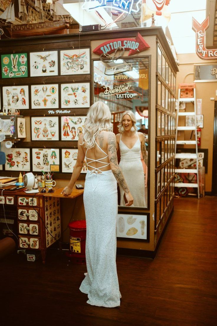 a woman standing in front of a store window with tattoos on it's back