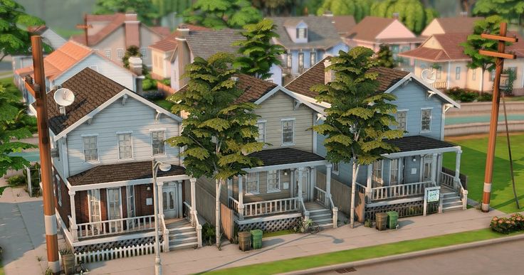 a group of houses sitting next to each other on a city street with trees in front of them