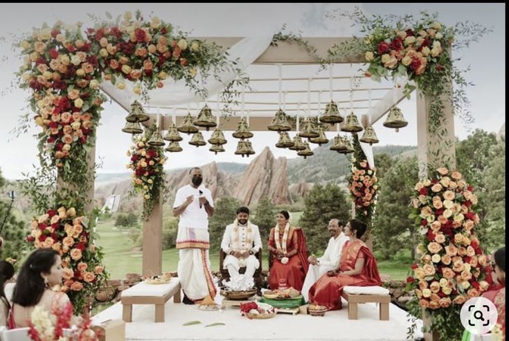 a group of people sitting on top of a white bench under a gazebo covered in flowers