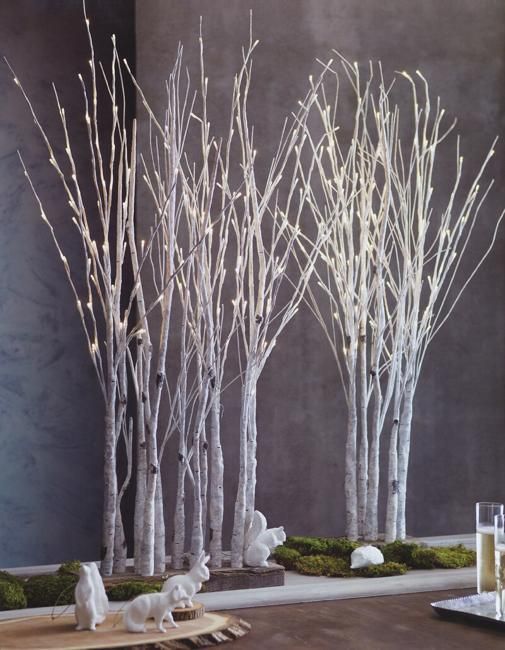 three white trees are sitting in front of a wall with moss and rocks on it