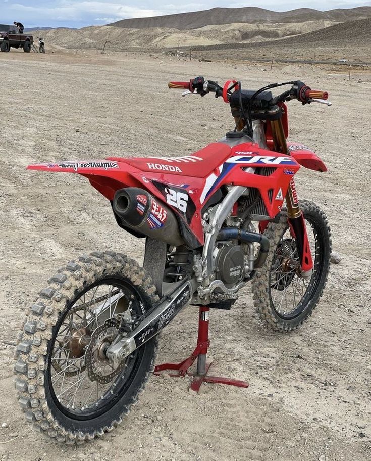 a red dirt bike parked on top of a dirt field