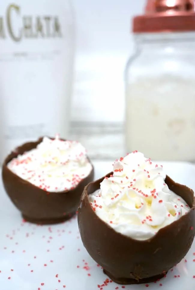 two chocolate covered desserts sitting on top of a white plate next to a bottle of milk