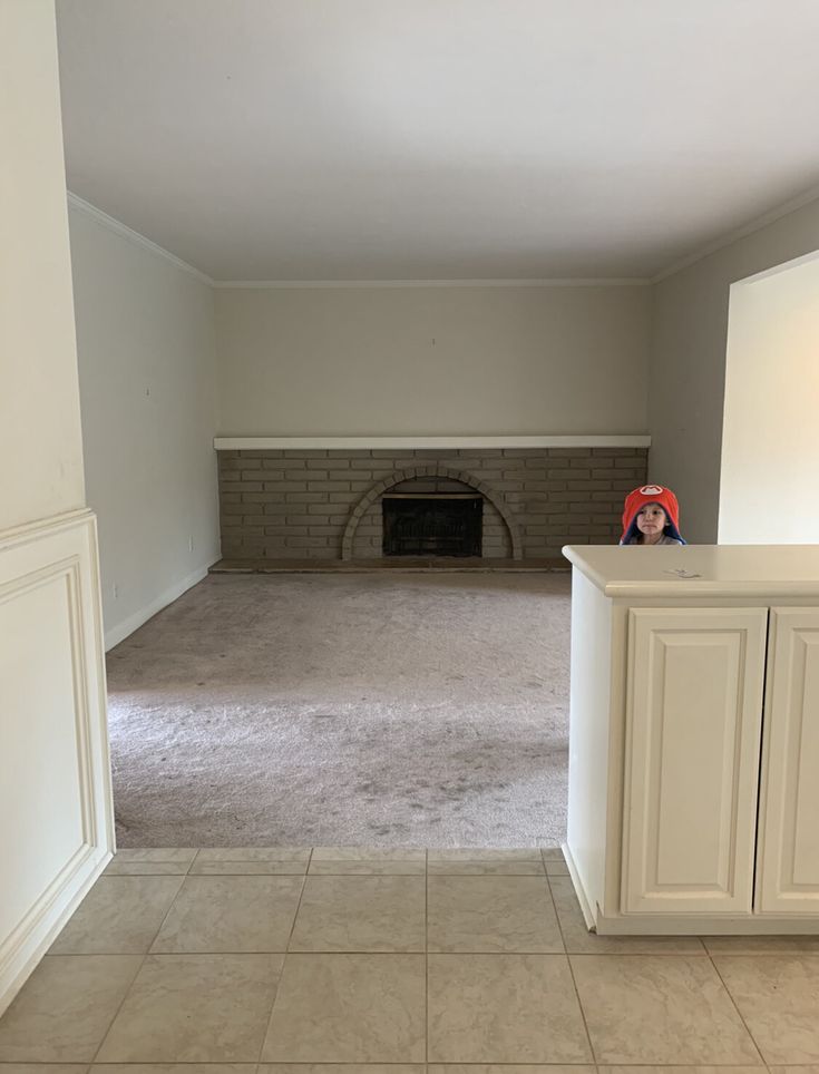 an empty living room with a fireplace in the middle and tile flooring on the other side