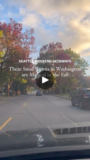 a car driving down a street next to a tree filled road with fall leaves on the trees