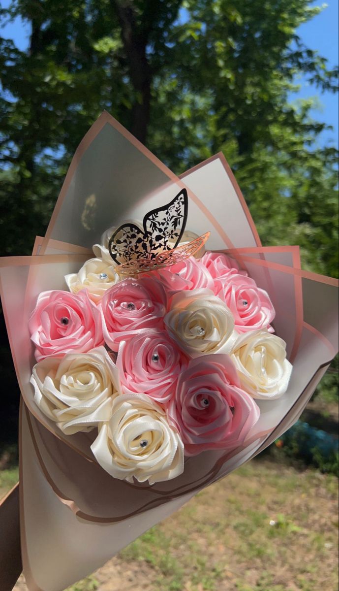 a bouquet of roses with a butterfly on top is held in front of the camera