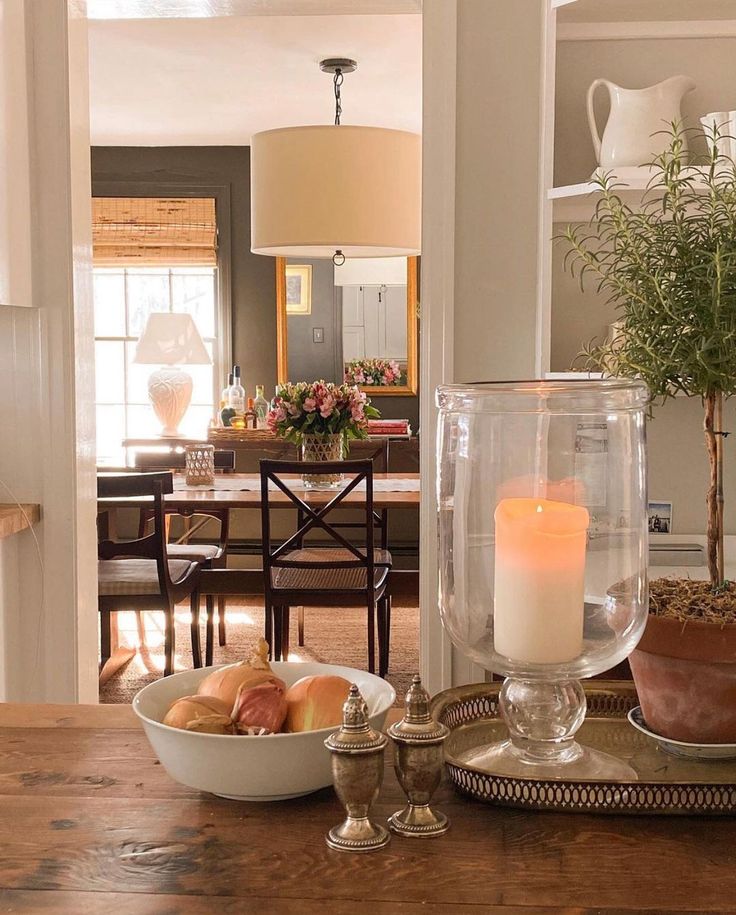 a dining room table with plates and bowls on it, candles in the centerpiece